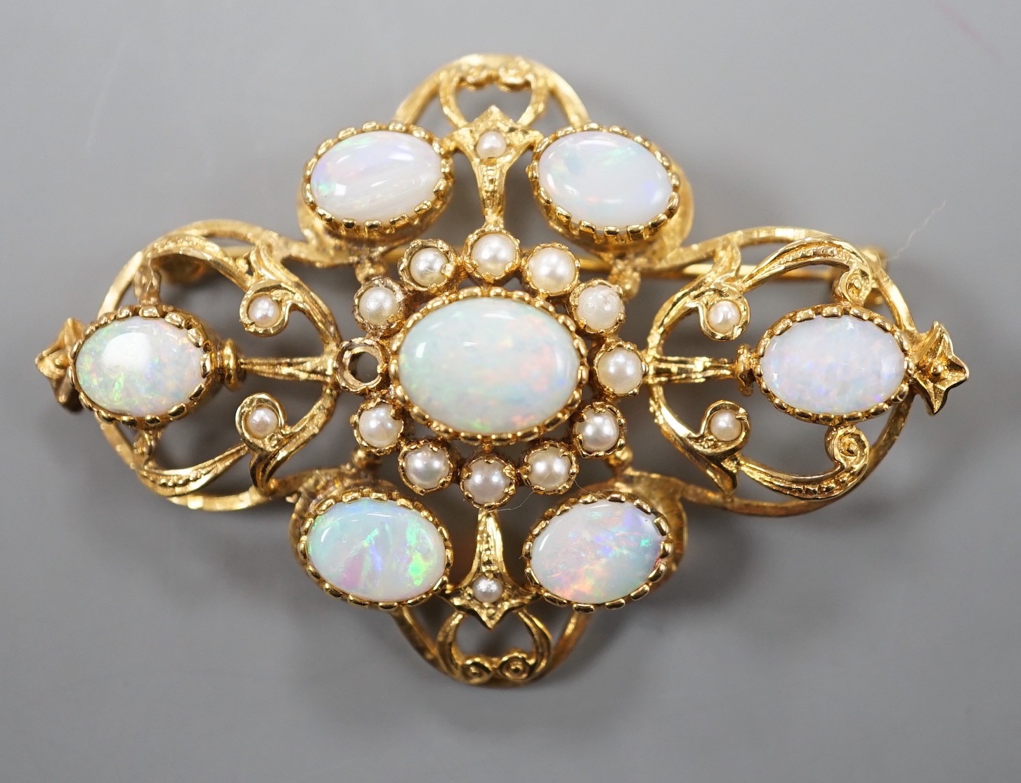 An early 1970's 9ct gold, graduated oval white opal and split pearl set brooch, of quatrefoil shape (pearl missing), 48mm, gross weight 9.3 grams.